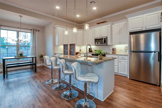 kitchen featuring white cabinetry, light stone counters, stainless steel appliances, and decorative light fixtures