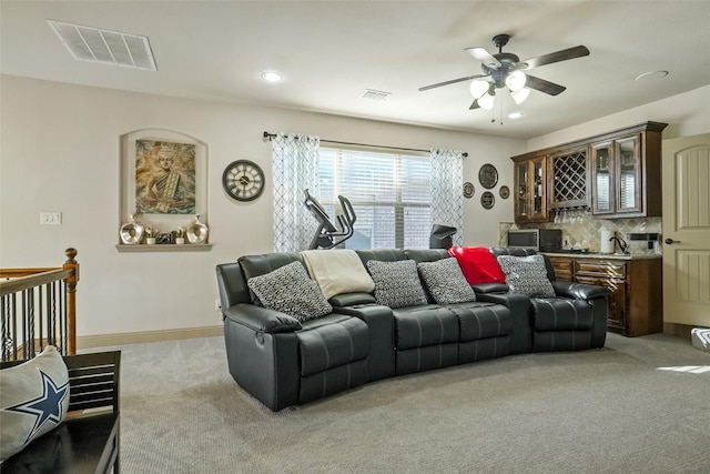 living room featuring ceiling fan, bar area, and light carpet