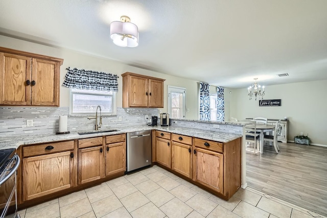 kitchen featuring appliances with stainless steel finishes, tasteful backsplash, sink, kitchen peninsula, and light stone countertops