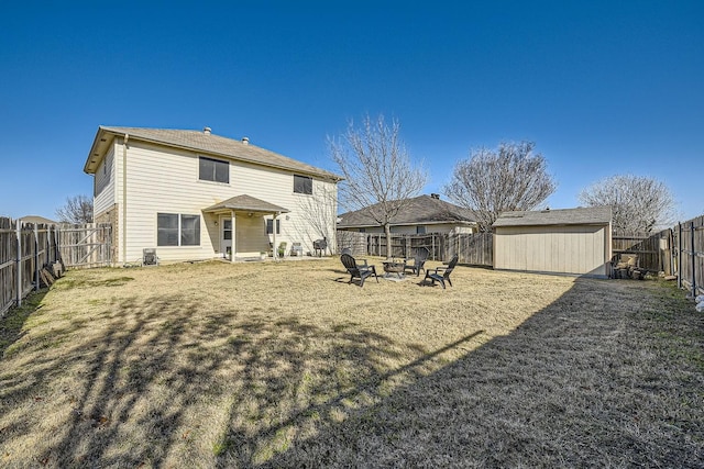 rear view of property featuring a fire pit, a lawn, and a storage unit