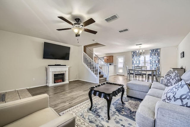 living room with ceiling fan with notable chandelier and light hardwood / wood-style flooring