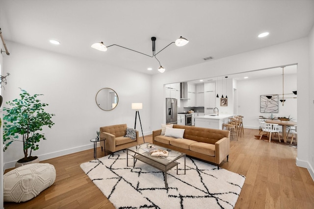 living room featuring sink and light hardwood / wood-style flooring