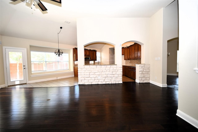 unfurnished living room with hardwood / wood-style flooring, high vaulted ceiling, and ceiling fan