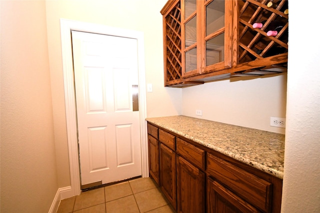 bar with light stone countertops and light tile patterned floors