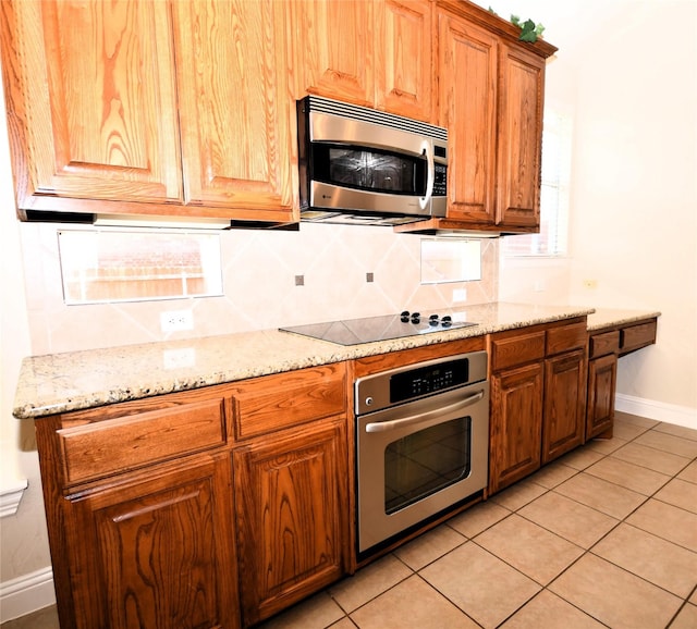 kitchen with light stone counters, appliances with stainless steel finishes, light tile patterned flooring, and decorative backsplash