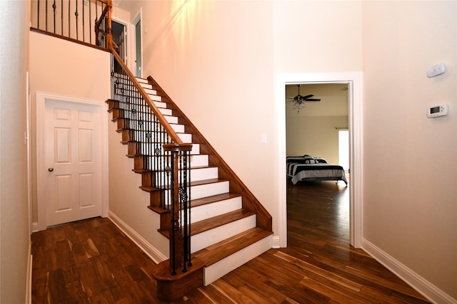 stairs with hardwood / wood-style flooring and a towering ceiling