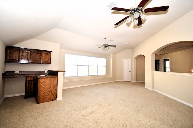 unfurnished living room with vaulted ceiling, sink, light colored carpet, and ceiling fan