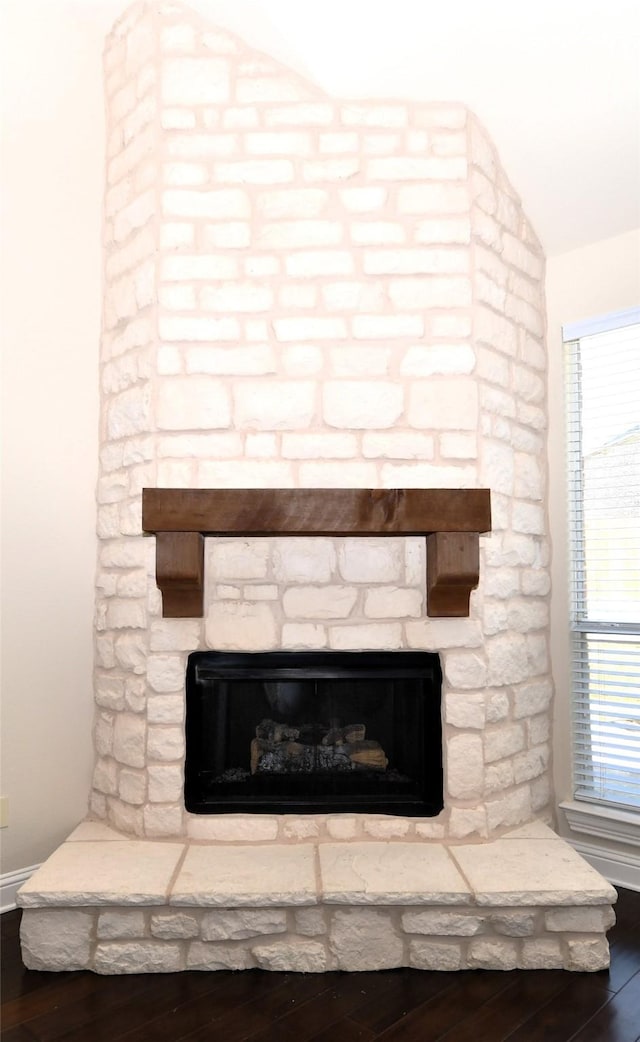 details with hardwood / wood-style flooring and a stone fireplace