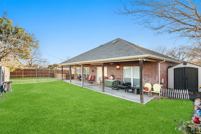 rear view of property with a storage unit, a yard, and a patio area