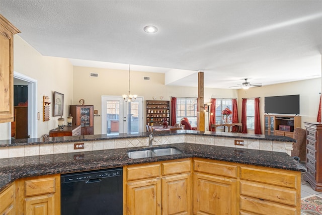 kitchen featuring sink, dishwasher, dark stone countertops, ceiling fan with notable chandelier, and kitchen peninsula