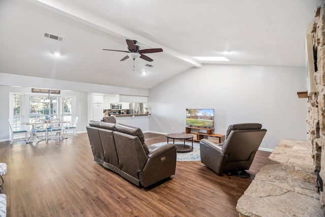 living room with dark wood-type flooring, ceiling fan, a fireplace, and vaulted ceiling with beams