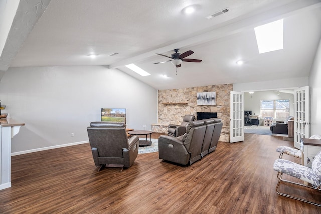 living room with lofted ceiling with skylight, a fireplace, dark hardwood / wood-style flooring, ceiling fan, and french doors