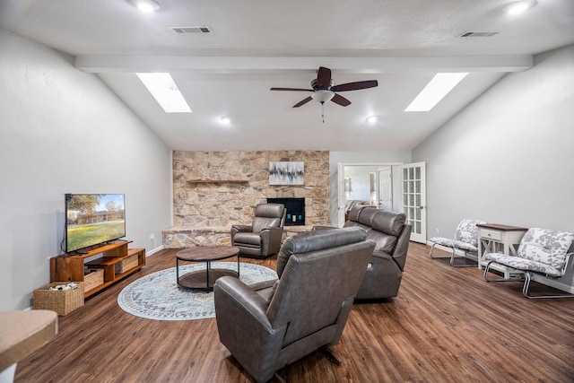 living room featuring a fireplace, dark wood-type flooring, lofted ceiling with skylight, and ceiling fan