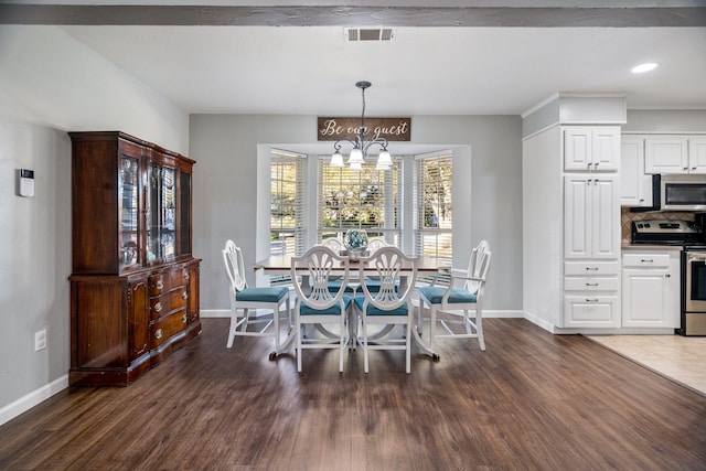 dining area with dark wood-type flooring and an inviting chandelier