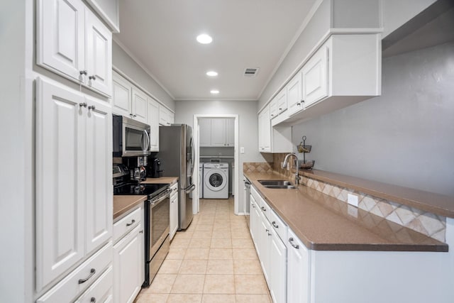 kitchen featuring sink, white cabinetry, stainless steel appliances, tasteful backsplash, and washing machine and clothes dryer