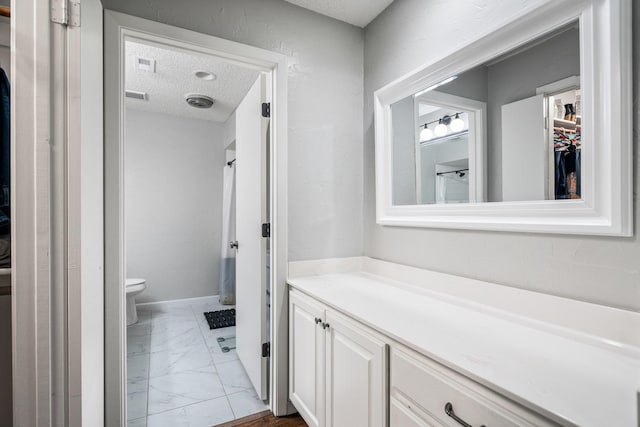 bathroom with vanity, toilet, and a textured ceiling