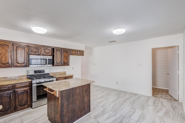 kitchen featuring dark brown cabinets, a kitchen island, and appliances with stainless steel finishes