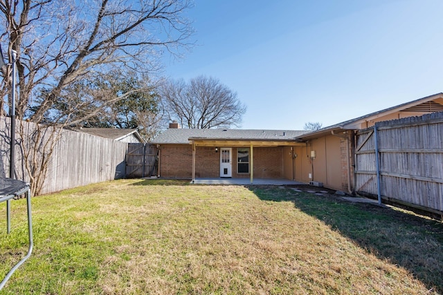 back of property featuring a patio, a yard, and a trampoline