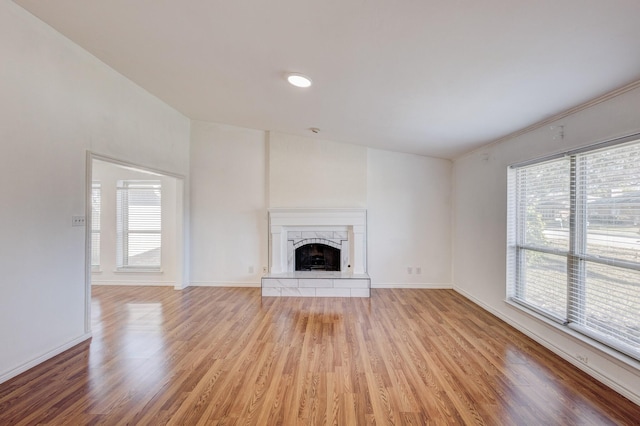 unfurnished living room featuring a high end fireplace and light wood-type flooring