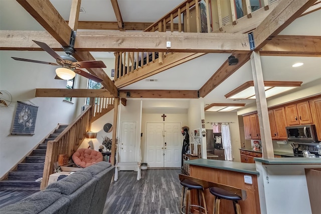 kitchen with a breakfast bar, a high ceiling, ceiling fan, dark wood-type flooring, and beam ceiling