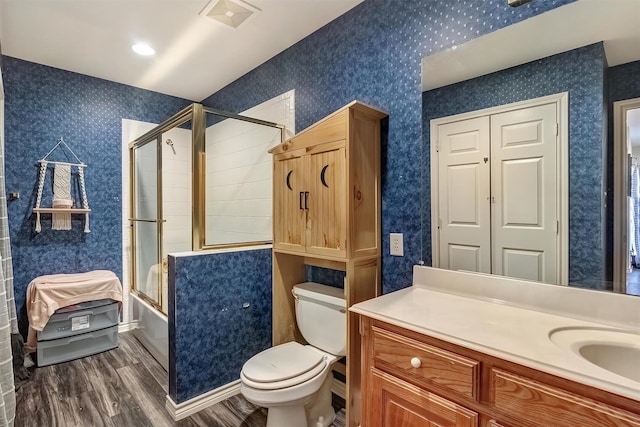 full bathroom featuring vanity, combined bath / shower with glass door, hardwood / wood-style floors, and toilet