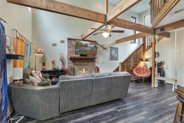 living room featuring beamed ceiling, a towering ceiling, dark hardwood / wood-style floors, and a brick fireplace