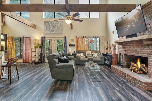 living room with a fireplace, a high ceiling, ceiling fan, dark wood-type flooring, and french doors