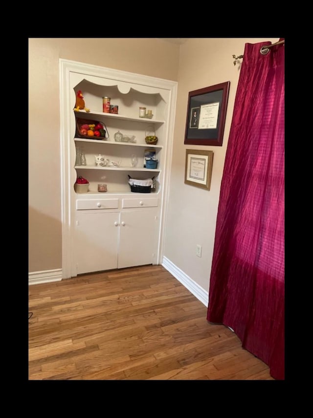 corridor with hardwood / wood-style flooring and built in shelves