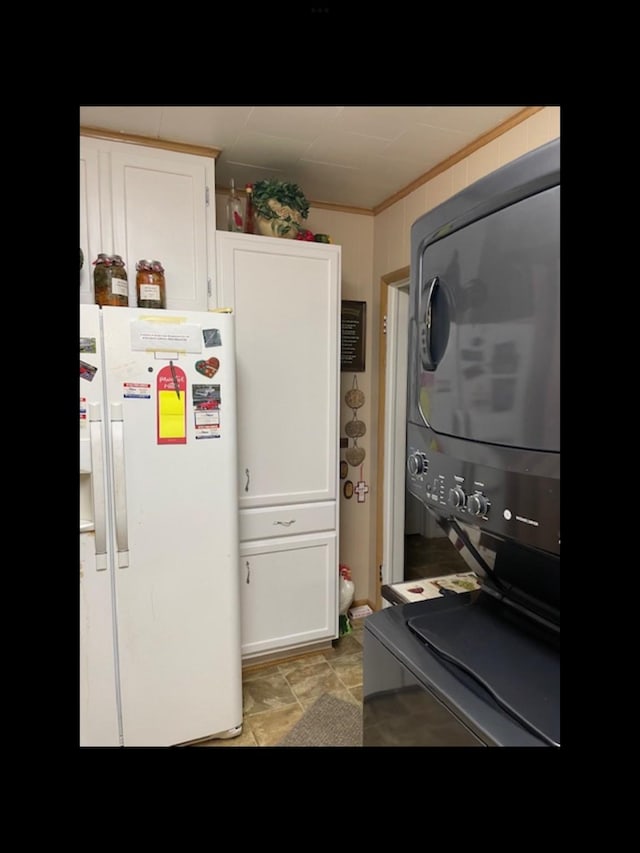 kitchen with white cabinetry, stacked washing maching and dryer, and white fridge