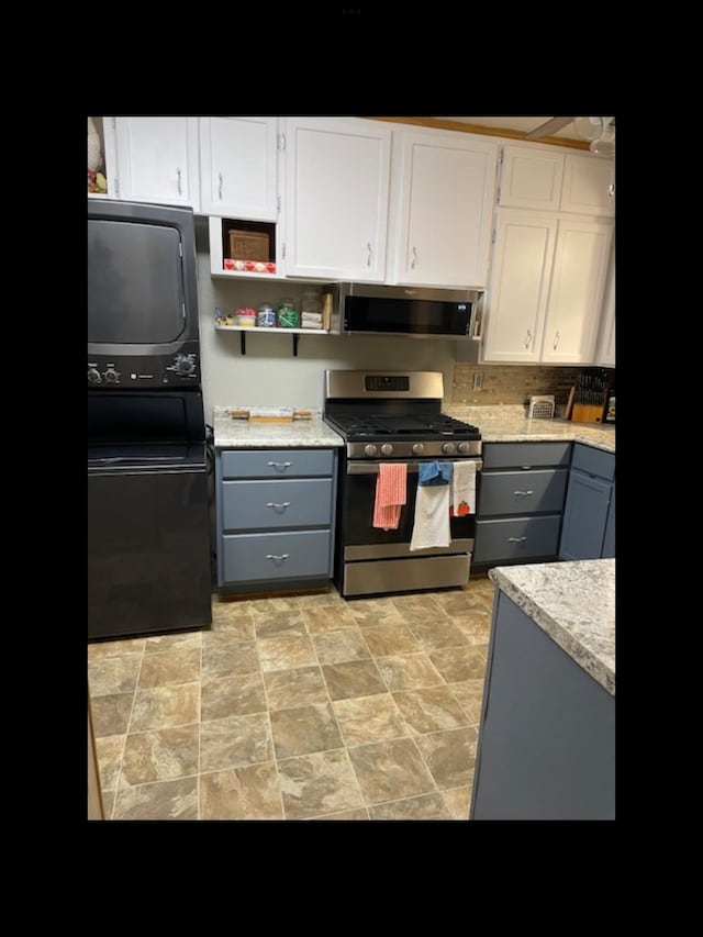 kitchen with gray cabinets, white cabinetry, appliances with stainless steel finishes, and stacked washer / drying machine