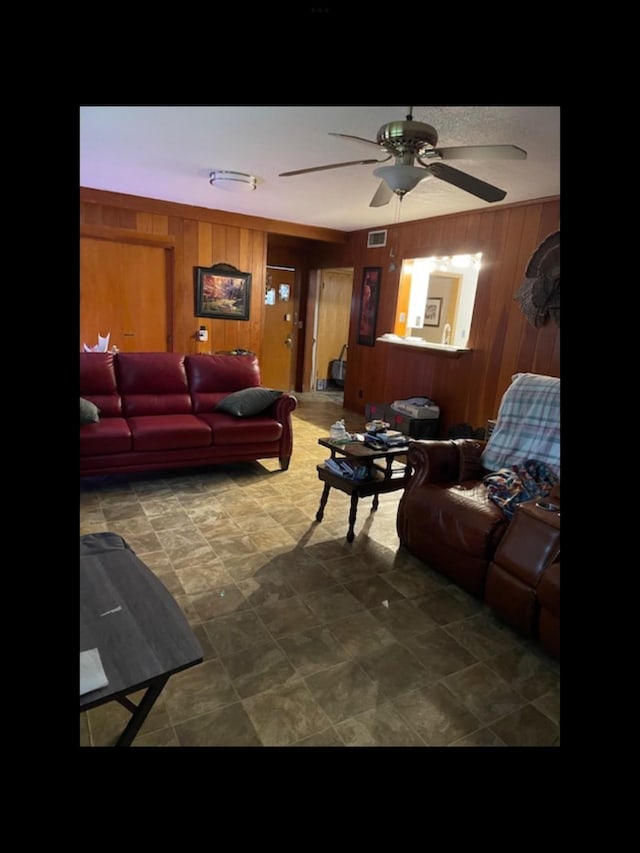 living room with ceiling fan and wood walls