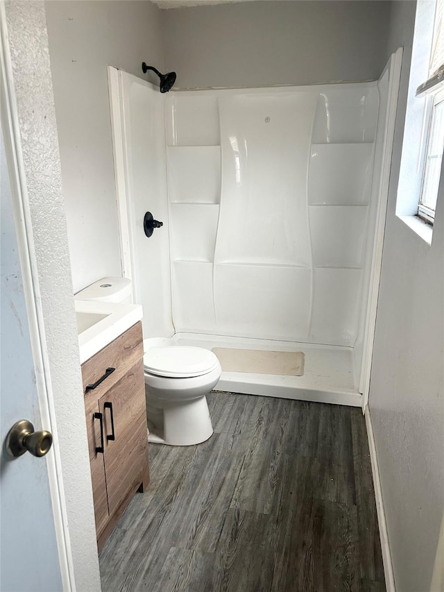 bathroom featuring vanity, hardwood / wood-style flooring, toilet, and a shower