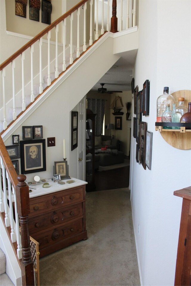 stairs with ceiling fan, a towering ceiling, and hardwood / wood-style floors