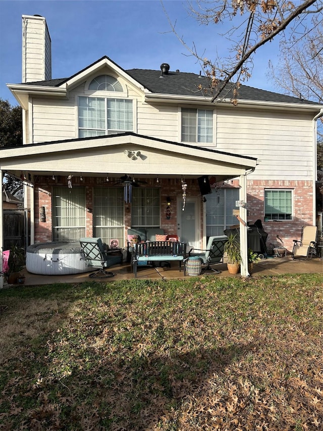 view of front of home featuring a porch, brick siding, a lawn, and a chimney