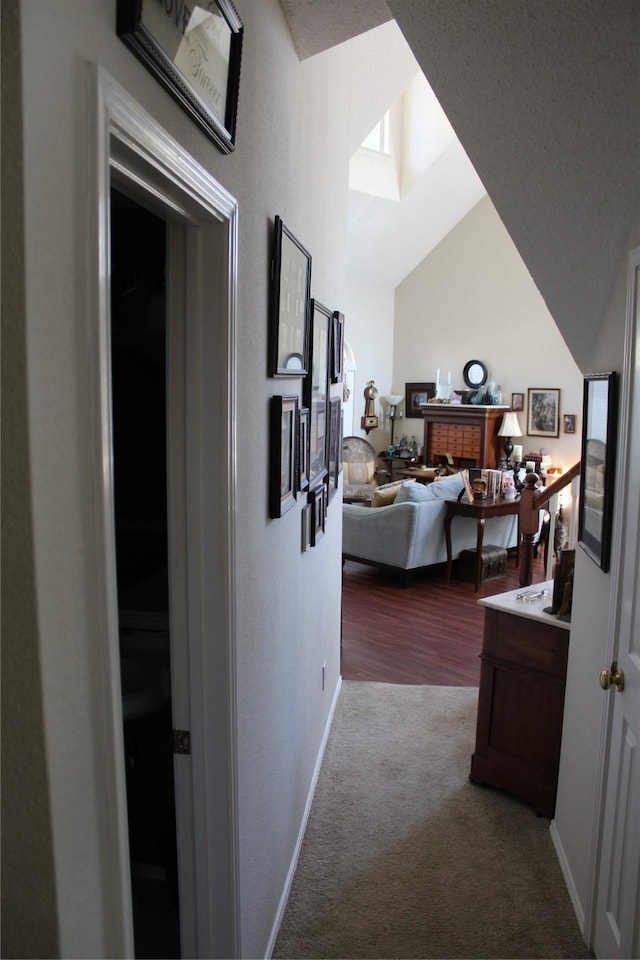 corridor with vaulted ceiling and carpet flooring