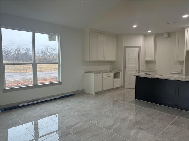 kitchen with plenty of natural light, white cabinets, and light stone counters