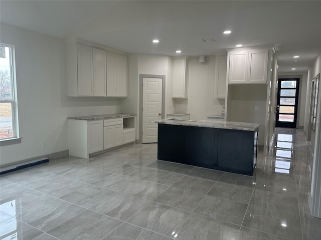 kitchen with a center island, white cabinets, and light stone counters