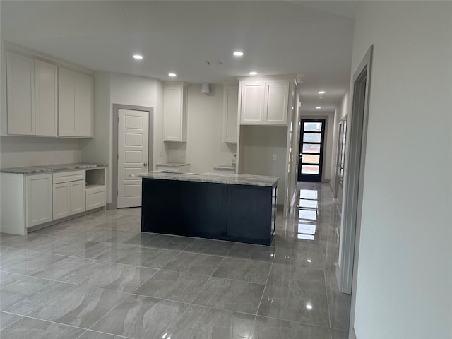 kitchen featuring light stone countertops, white cabinets, and a kitchen island