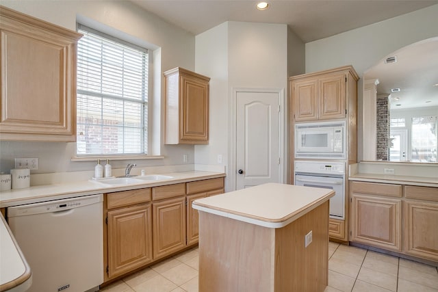 kitchen featuring light brown cabinetry, sink, white appliances, and a kitchen island