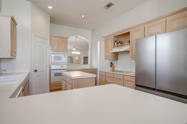 kitchen featuring white appliances, light brown cabinetry, a center island, and sink