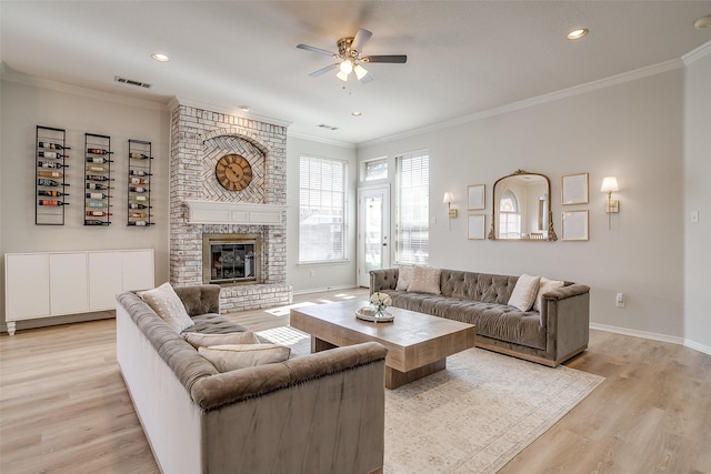 living room featuring ornamental molding, a brick fireplace, ceiling fan, and light hardwood / wood-style floors