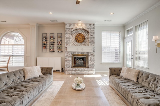 living room featuring a brick fireplace, crown molding, and light wood-type flooring