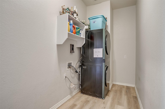 washroom featuring stacked washer / drying machine and light hardwood / wood-style floors