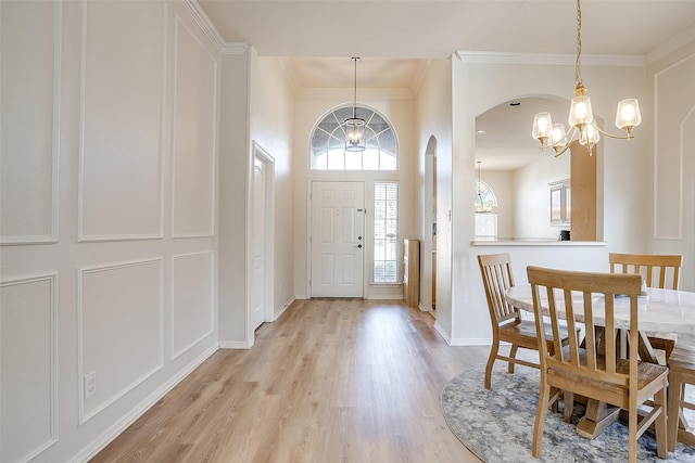 foyer entrance with ornamental molding, a chandelier, and light hardwood / wood-style flooring