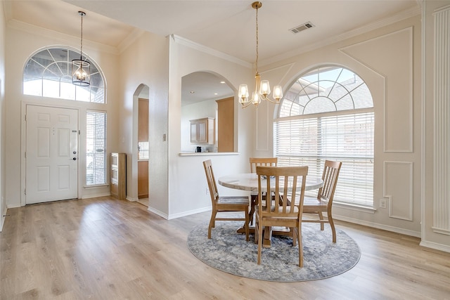 dining space with crown molding, light hardwood / wood-style flooring, and a chandelier