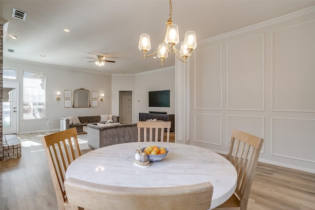 dining area featuring ornamental molding, ceiling fan with notable chandelier, and light hardwood / wood-style flooring