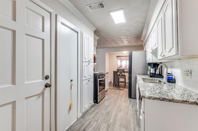 kitchen featuring sink, white cabinetry, stainless steel range with gas cooktop, light stone countertops, and backsplash