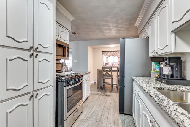 kitchen with white cabinetry, sink, backsplash, light stone counters, and stainless steel gas range