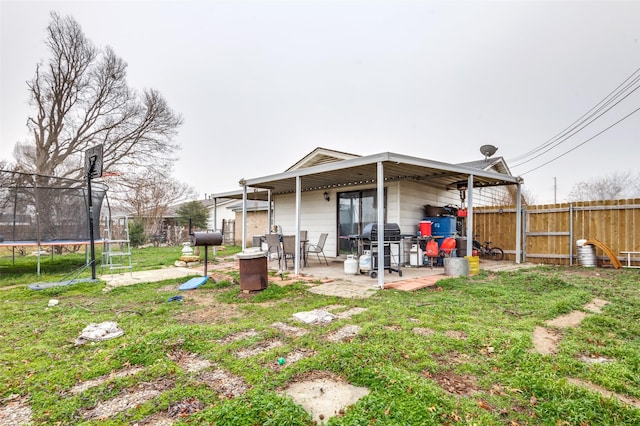 back of property with a patio, a trampoline, and a lawn