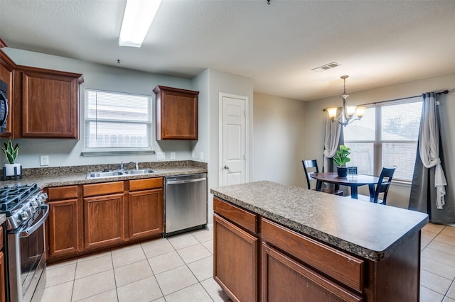 kitchen with sink, light tile patterned floors, stainless steel appliances, a center island, and a notable chandelier